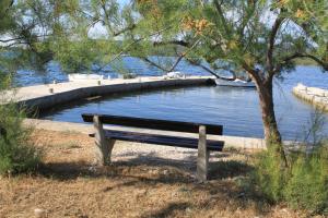 a park bench sitting next to a body of water at Apartments by the sea Veli Rat, Dugi otok - 438 in Veli Rat