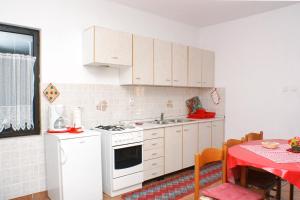 cocina con armarios blancos y mesa con mantel rojo en Apartments by the sea Mandre, Pag - 523, en Kolan