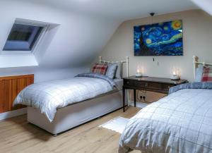 a bedroom with two beds and a desk and a painting at Kirkinner Cottage in Kirkinner