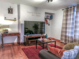 ein Wohnzimmer mit einem TV, einem Sofa und einem Tisch in der Unterkunft Kirkinner Cottage in Kirkinner