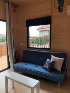 a blue couch in a room with a window at Cabañas Compostela - Cabaña A Fervenza in Santiago de Compostela