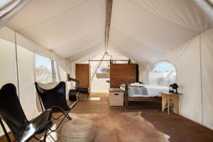 a tent with a bed and a chair in a room at Under Canvas Grand Canyon in Valle