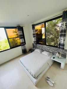 ein Schlafzimmer mit einem Bett und zwei großen Fenstern in der Unterkunft keur manga2 in Somone