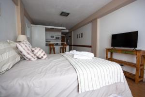 a bedroom with a white bed with a flat screen tv at Tu Apart En Bariloche 34 in San Carlos de Bariloche