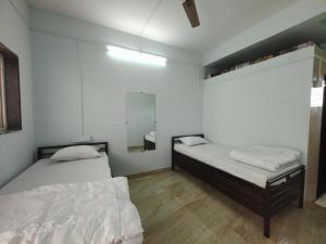 1 dormitorio con 2 camas y espejo en Fulgulab Lawns and Home Stay, en Junnar