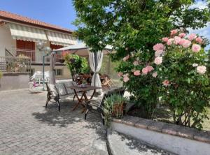 un patio con mesa, sombrilla y rosas en Lo Campo, en Montella