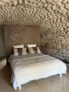 um quarto com uma cama com uma parede de pedra em GITE DE LA CAPPELLA - CHAMBRE D'HÔTES A VOLTA em Aubenas