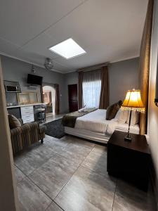 Silken Trap Guest House NO LOADSHEDDING في جوهانسبرغ: غرفة نوم بسرير واريكة ومصباح