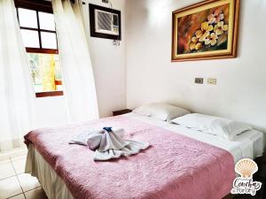 1 dormitorio con cama rosa y albornoz en Pousada Conchas de Paraty, en Paraty