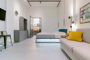 Habitación blanca con 2 camas y sofá en MONO Apartments en Bolonia