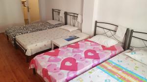 ein Zimmer mit 2 Betten und einem Tisch dazwischen in der Unterkunft SIXORIZON NEW PRIVATE APARTMENT IN THESSALONIKI IPPOKRATEIO gr in Thessaloniki