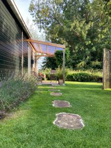 einen Garten mit einer Pergola und einer Terrasse in der Unterkunft Vakantiehuisje De Waddenuil 