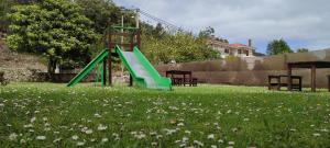 a green slide in a field of grass with flowers at La Chopera in Ribadesella