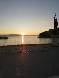 um pôr-do-sol na praia com uma estátua em primeiro plano em Apartment NAUM M em Ohrid