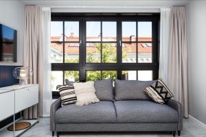 - un salon avec un canapé et une grande fenêtre dans l'établissement H11 Aparthotel, à Cracovie