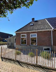 una casa de ladrillo con una valla delante de ella en Wierums Huske aan de Waddenzee Unesco Werelderfgoed, en Wierum