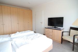 1 Schlafzimmer mit 2 Betten, einem TV und einem Stuhl in der Unterkunft STRANDIDYLL, 134 - Typ B4 in Grömitz