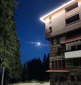 een nachtzicht op een gebouw met de maan in de lucht bij Апартаменти и стаи за гости "Алекс" in Pamporovo