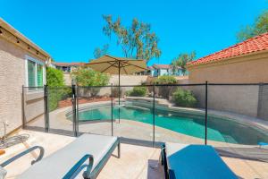 a swimming pool with a fence and an umbrella at Poolside Getaway in Scottsdale