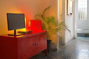 une commode rouge avec un moniteur et une plante dessus dans l'établissement Casa Tortilla Sant Antoni, à Barcelone
