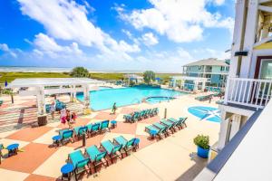 - une vue sur la piscine du complexe avec des chaises bleues dans l'établissement Stunning Sunsets Steps from Pool Lazy River Ocean Bay Views, à Galveston