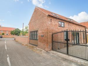 a brick building with a gate next to a street at Lifford Coach House in Sutton upon Trent