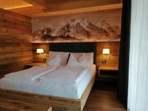 テーゼロにあるDOLOMITES B&B - Suites, Apartments and SPAのベッドルーム1室(白いベッド1台、ナイトスタンド2台付)