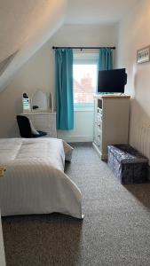 a bedroom with a bed and a television and a window at Bexhill Sea View Flat 3 in Bexhill