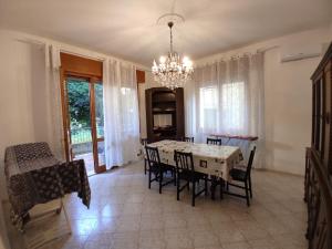 uma sala de jantar com uma mesa e cadeiras e um lustre em Casa al mare em Lido di Venezia