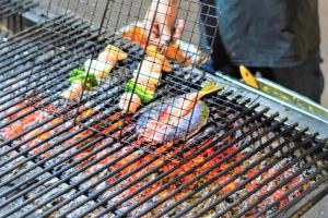 een persoon kookt hotdogs op een grill bij Warna Beach Hotel in Gili Trawangan