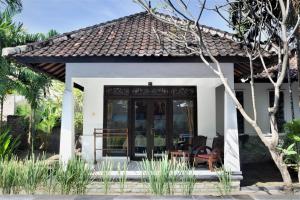 a small white house with a black door at Warna Beach Hotel in Gili Trawangan