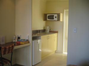 a kitchen with a white refrigerator and a microwave at Shortland Court Motel in Thames