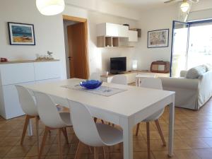 een keuken en een woonkamer met een witte tafel en stoelen bij Brezza Marina Apartment in Trapani