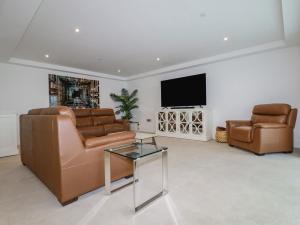 a living room with leather furniture and a flat screen tv at 13 Cliff Edge in Newquay