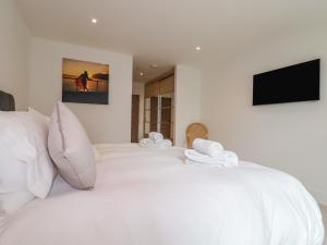 a white bed with white pillows and a flat screen tv at 13 Cliff Edge in Newquay