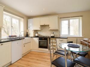 a kitchen with white cabinets and a table with chairs at Canal View in Todmorden