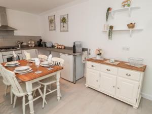 uma cozinha com uma mesa de madeira e armários brancos em Horseshoe Cottage em Coldstream