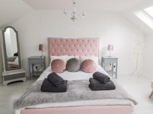 a bedroom with a pink bed with pillows and a mirror at Horseshoe Cottage in Coldstream