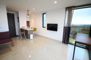 a living room with a large window and a television at Vista Resort Jeju in Jeju