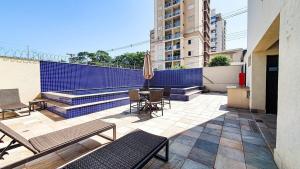 un patio con sillas, mesas y una pared azul en Nova Aliança 66-wifi-estacionamento-pet friendly, en Ribeirão Preto