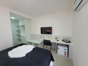 a bedroom with a bed and a desk and a tv at Edifício Royale flat 230 in Cabo Frio