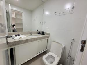 uma casa de banho com um WC, um lavatório e um espelho. em Edifício Royale flat 230 em Cabo Frio