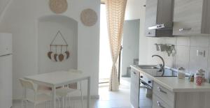 a white kitchen with a sink and a table at Appartamenti Boho Chic in Sannicandro di Bari