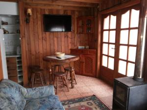 a living room with a small table and a tv at Cabaña Ruca Quimey in Villarrica