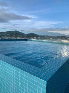 a blue tile swimming pool with a city in the background at Edifício Royale flat 230 in Cabo Frio