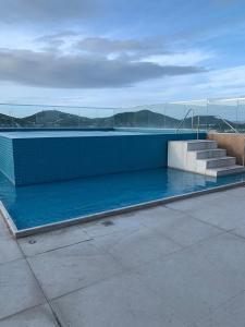 uma piscina com escadas e água azul em Edifício Royale flat 230 em Cabo Frio