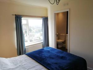 een slaapkamer met een blauwe deken op een bed met een raam bij Country Home with Gardens in Newtown