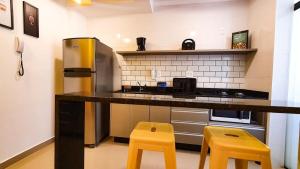 a kitchen with a counter and two yellow stools at Nova Aliança 103-wifi-estacionamento-3 hóspedes in Ribeirão Preto