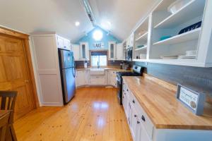 La cuisine est équipée de placards blancs et d'un réfrigérateur bleu. dans l'établissement The charming Glenn Cottage! Walk to Lake Michigan!, à Fennville