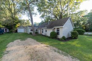 une maison blanche avec un arbre dans la cour dans l'établissement The charming Glenn Cottage! Walk to Lake Michigan!, à Fennville
